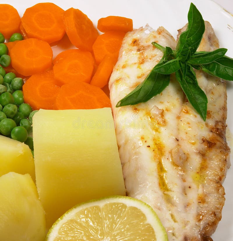 Pesce alla griglia, carote, piselli, patate e limone.