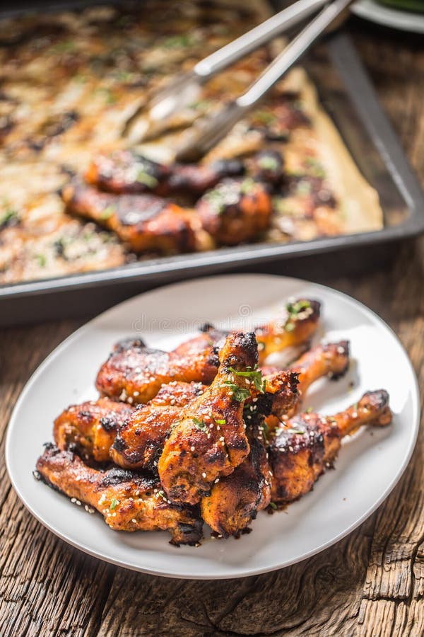 Grilled hicken BBQ ног с травами и сезамом специй на испеченной бумаге Зажаренная в духовке еда птицы на белой плите стоковые изображения Grilled hicken BBQ ног с травами и сезамом специй на испеченной бумаге Зажаренная в духовке еда птицы на белой плите стоковые изображения