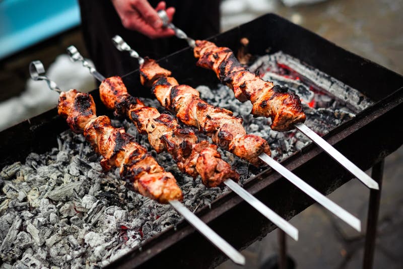 Grilled kebab cooking on metal skewer. Roasted meat cooked at barbecue. Traditional eastern dish, shish kebab. Grill on