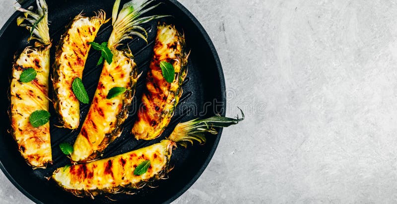 Grilled pineapple with fresh mint in cast iron pan on gray stone background stock photo Grilled pineapple with fresh mint in cast iron pan on gray stone background stock photo