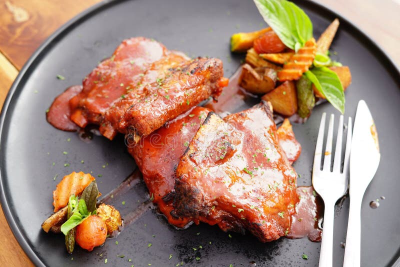 Grilled Pork Ribs and Side Dishes on a Black Plate Stock Photo - Image