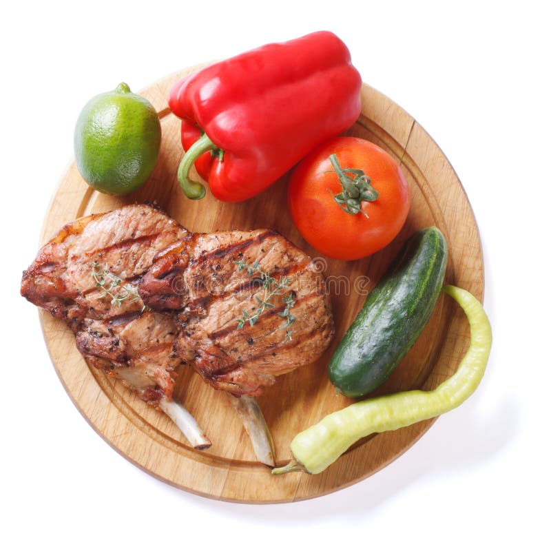 Grilled pork and vegetables on a cutting board isolated top view