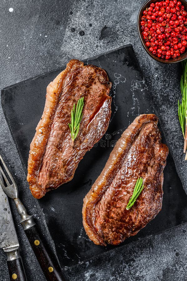 Grilled Ramp Cap Steak on a Stone Chopping Board. Black Background
