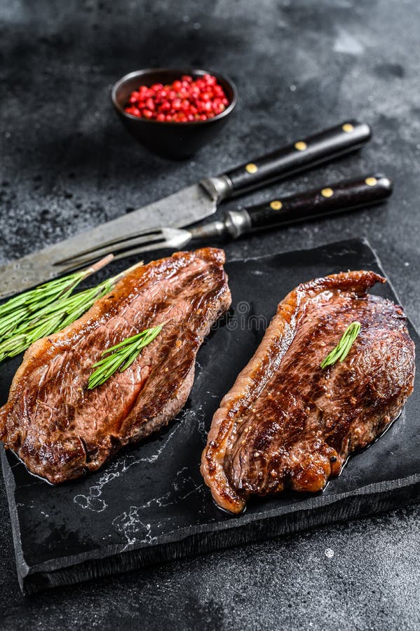 Grilled Ramp Cap Steak on a Stone Chopping Board. Black Background