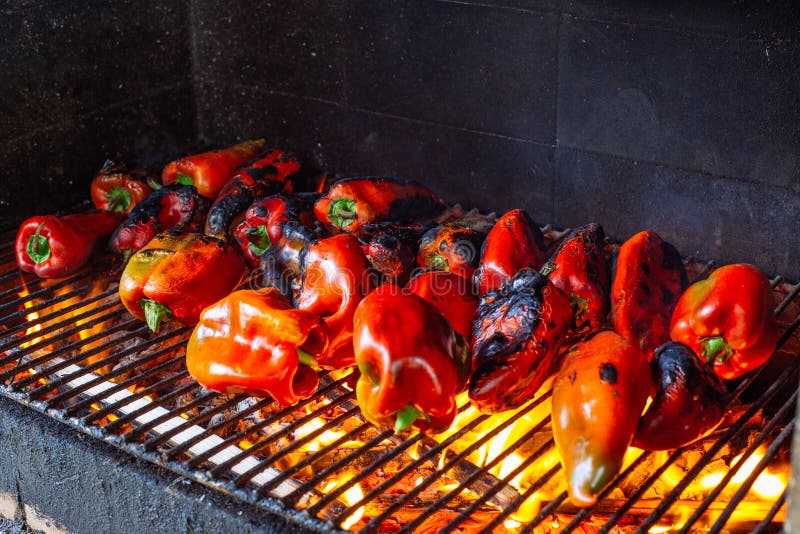 Grilled red bell peppers, fire burning on grill barbecue