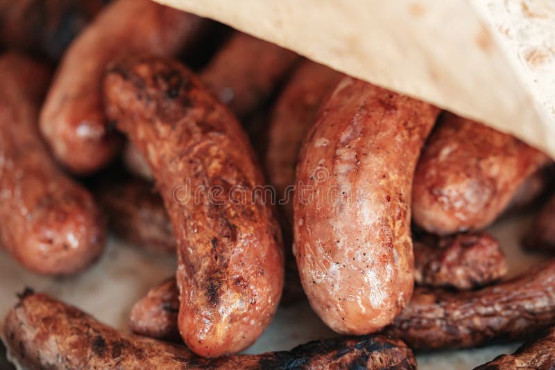 Grilled sausages or bratwurst on grill with smoke and flame