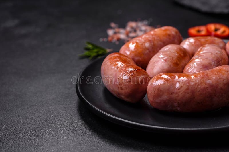 Grilled Sausages with Spices and Herbs on a Black Background Stock