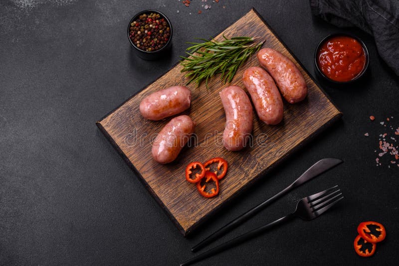 Grilled Sausages with Spices and Herbs on a Black Background Stock