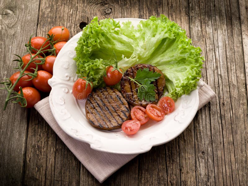 Grilled seitan with tomatoes. And salad stock image