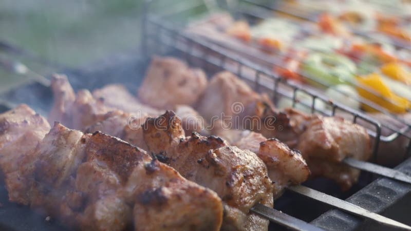 Grilled shish kebab on metal skewer. Chef hands cooking roasted meat barbecue with lots of smoke. BBQ fresh beef chop