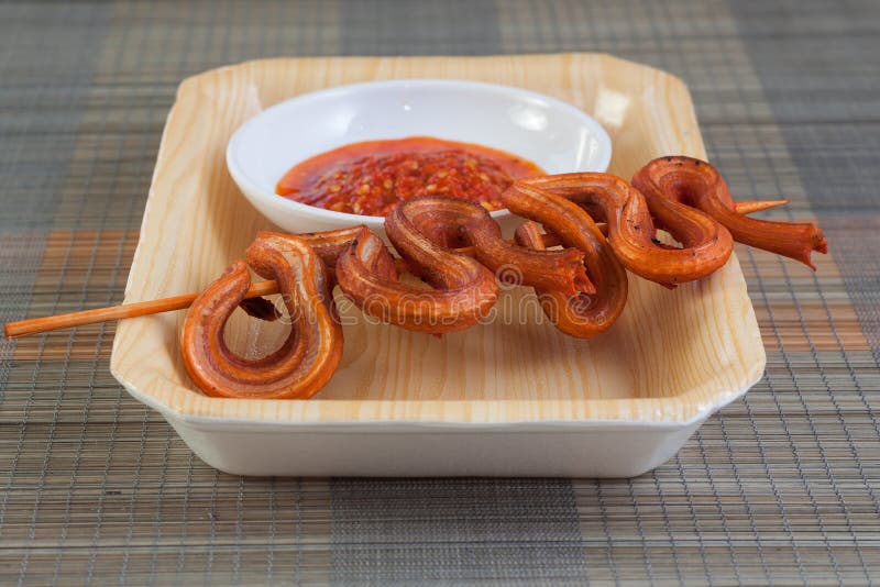Grilled Snake on Skewer with Chili Sauce and Rice on White Plate on Mat