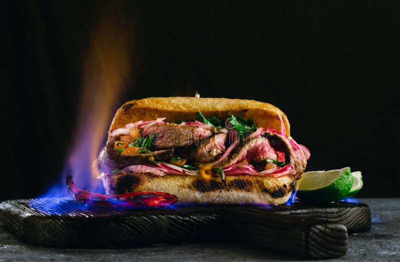 Grilled spicy steak sandwiches steak in fire flame wooden cutting boards on dark background
