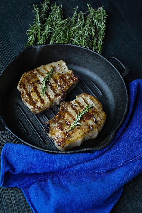 Grilled steak on a round grill pan, decorated with spices for meat, rosemary on a dark wooden background. View from above royalty free stock images Grilled steak on a round grill pan, decorated with spices for meat, rosemary on a dark wooden background. View from above royalty free stock images