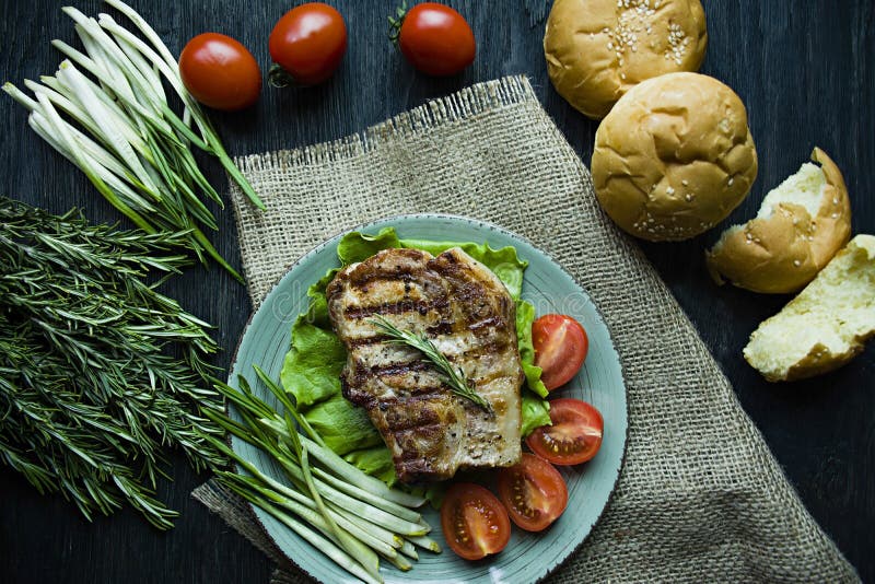 Grilled steak served on a plate, decorated with spices for meat, rosemary, greens and vegetables on a dark wooden background royalty free stock photos Grilled steak served on a plate, decorated with spices for meat, rosemary, greens and vegetables on a dark wooden background royalty free stock photos