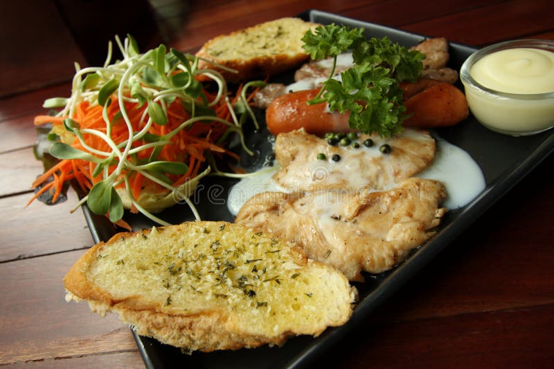 Grilled Steaks, Sausage, Garlic Bread and Salad Recipe Stock Photo