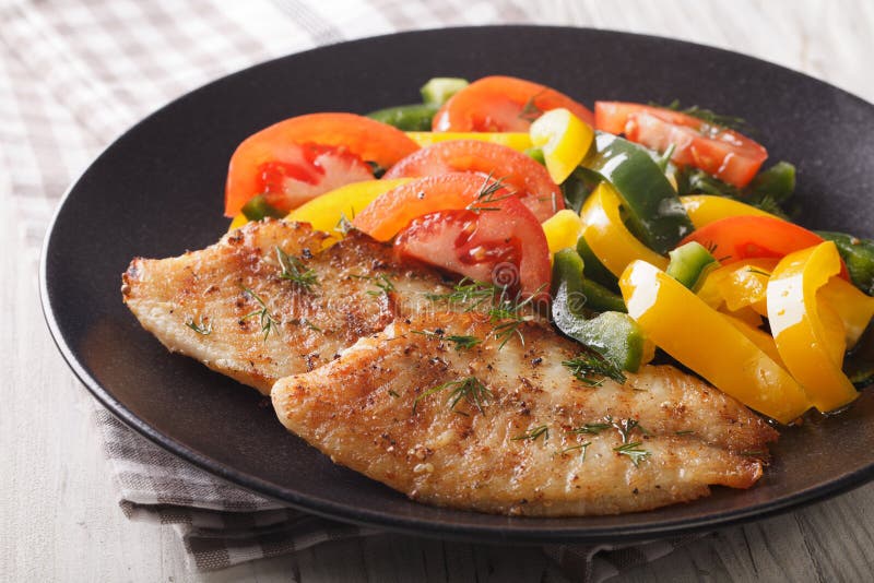 Grilled tilapia steak and fresh vegetable salad on a plate close-up. horizontal