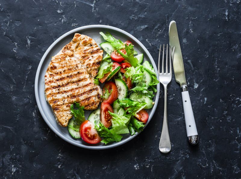 Grilled turkey chops and tomatoes, cucumbers, greens salad on a dark background, top. Healthy food diet concept royalty free stock images Grilled turkey chops and tomatoes, cucumbers, greens salad on a dark background, top. Healthy food diet concept royalty free stock images