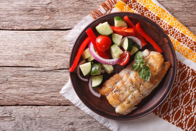 Grilled white fish and fresh vegetable salad on a plate. horizontal view from above. Grilled white fish and fresh vegetable salad on a plate. horizontal view from above