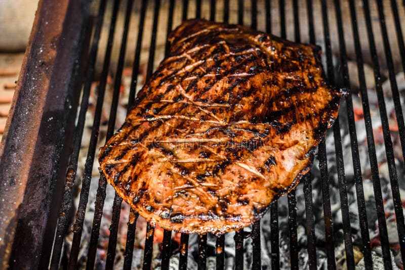 Grillen des marinierten Angus-Rindfleischbauchlappens auf heißem Kohlengrillgrill. Gebräu des kolossale halb garen Fleisch auf heißem Grillgrill mit Grillkennzeichen im Restaurantkamin