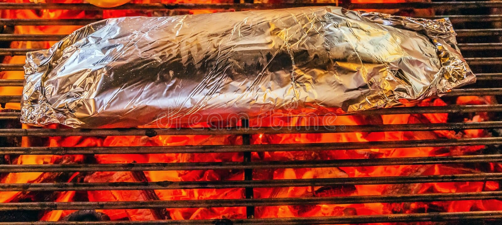 Meat Grilled in Foil on Flaming BBQ Grill. Barbecue cooking flaming grill  grid Food Background in aluminum foil. Portrait of the cooking food with  alu Stock Photo - Alamy