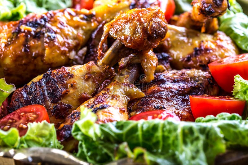 Grilling. Grilled chicken. Grilled chicken legs. Grilled chicken legs, lettuce and cherry tomatoes. Traditional cuisine.