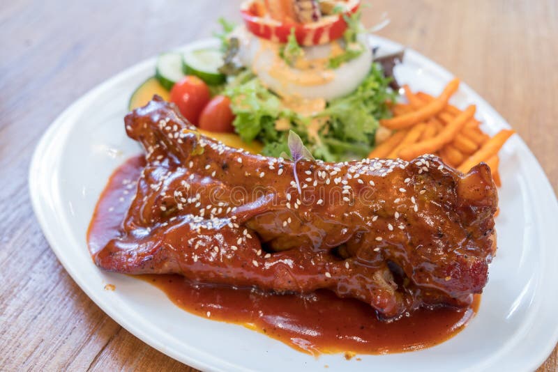 Grillschweinefleischrippen mit gebratenen Süßkartoffeln und Mischsalat auf weißer Platte lizenzfreie stockbilder Grillschweinefleischrippen mit gebratenen Süßkartoffeln und Mischsalat auf weißer Platte lizenzfreie stockbilder
