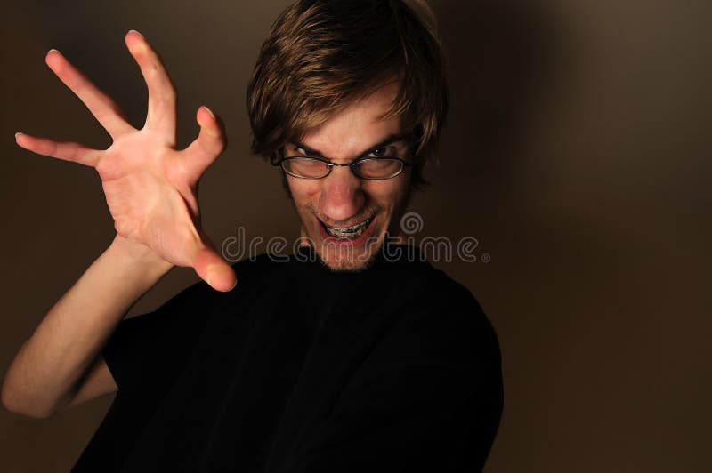 Young man ready to grab, touch, or something with his large hand claw. He looks like a techie with his glasses and braces on, but can qualify as any sort of regular person being scary. Young man ready to grab, touch, or something with his large hand claw. He looks like a techie with his glasses and braces on, but can qualify as any sort of regular person being scary.