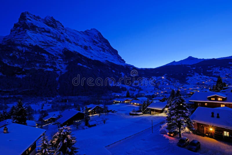 Grindelwalddorp bij schemer met MT De Eigerpiek op de achtergrond, sneeuw behandelde landschap in de winter, Zwitserland royalty-vrije stock foto's Grindelwalddorp bij schemer met MT De Eigerpiek op de achtergrond, sneeuw behandelde landschap in de winter, Zwitserland royalty-vrije stock foto's