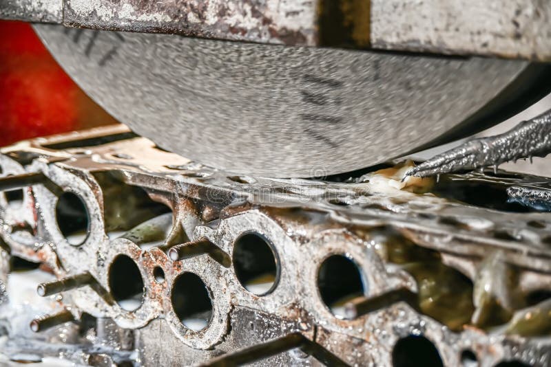 Grinding the cylinder head of a car engine on a water-cooled surface grinder stock photography