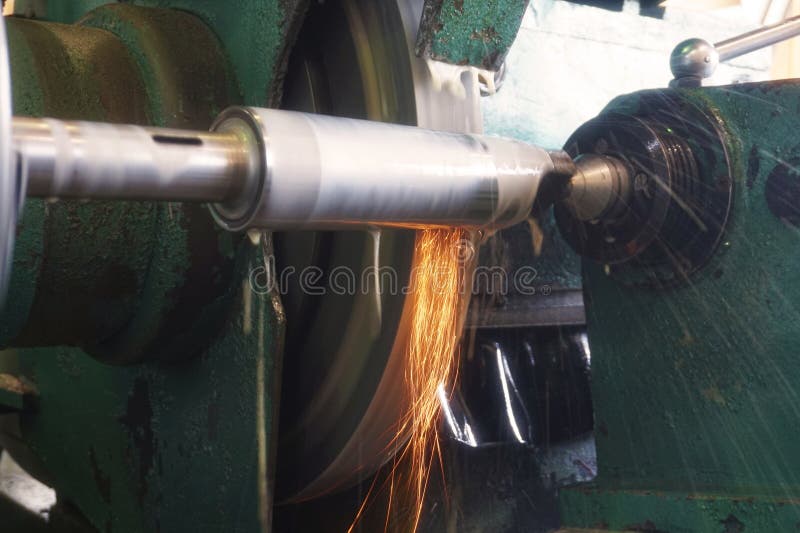 Grinding the shaft on the machine with sparks and cooling, at different angles. stock image