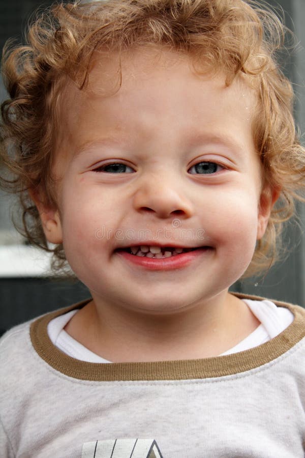 Grinning 2 yr old blond boy who lost a front tooth