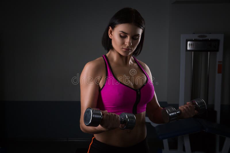 Grobe athletische Frau, die oben muscules mit Dummköpfen pumpt lizenzfreie stockfotos Grobe athletische Frau, die oben muscules mit Dummköpfen pumpt lizenzfreie stockfotos