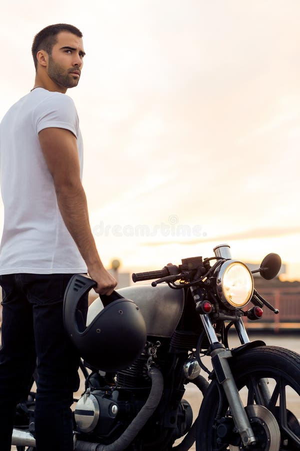 Grober Mann nahe seinem Caférennläufer-Gewohnheitsmotorrad stockfoto Grober Mann nahe seinem Caférennläufer-Gewohnheitsmotorrad stockfoto