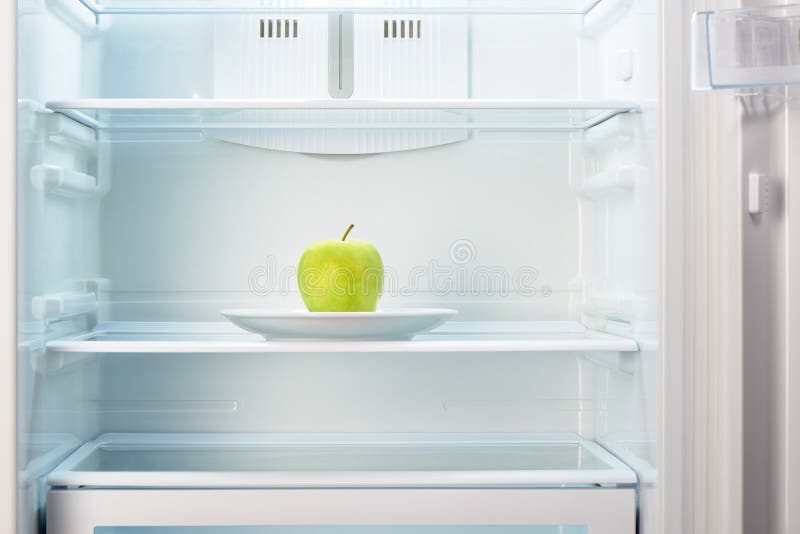 Groene appel op witte plaat in open lege ijskast stock foto's Groene appel op witte plaat in open lege ijskast stock foto's