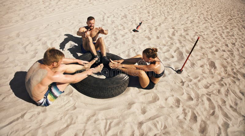 Groep atleten die crossfit oefeningsroutine op strand doen stock fotografie Groep atleten die crossfit oefeningsroutine op strand doen stock fotografie