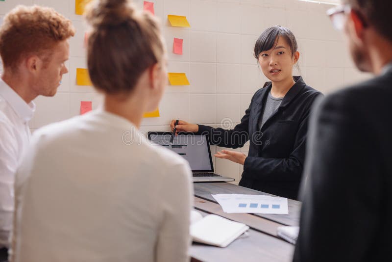 Groep bedrijfsmensen die gegevens over laptop bespreken op vergadering stock afbeelding Groep bedrijfsmensen die gegevens over laptop bespreken op vergadering stock afbeelding
