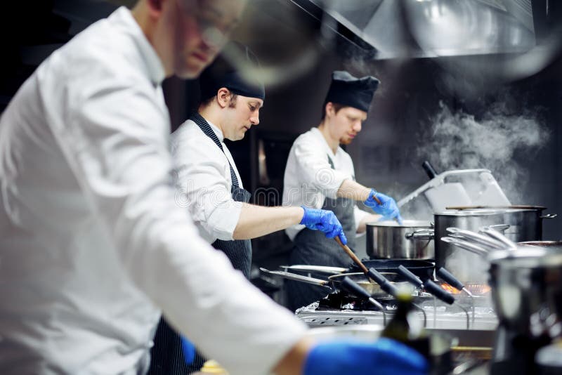 Groep chef-koks die in de keuken werken stock afbeeldingen Groep chef-koks die in de keuken werken stock afbeeldingen