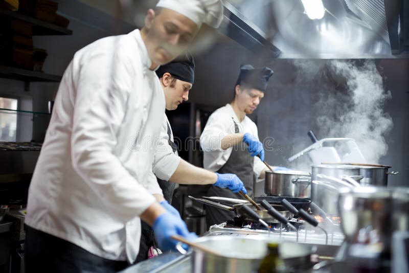 Groep chef-koks die in de keuken werken stock afbeelding Groep chef-koks die in de keuken werken stock afbeelding