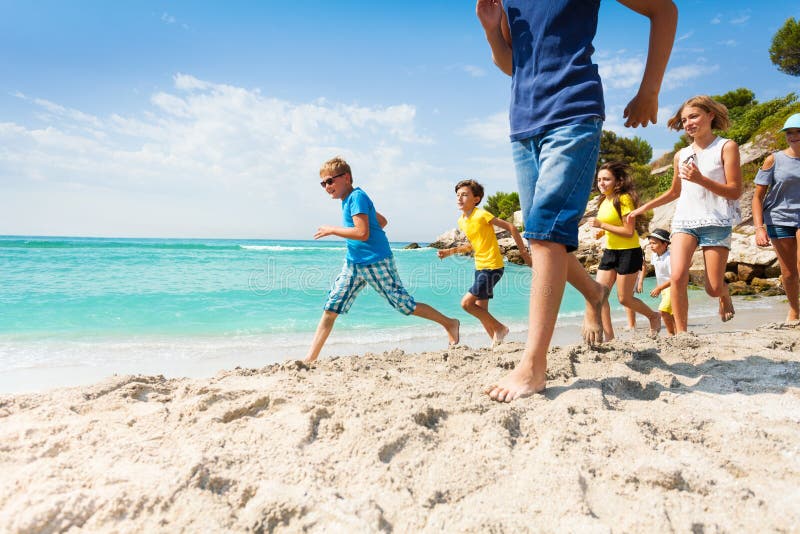 Groep die gelukkige jonge geitjes op wit zandstrand lopen stock fotografie Groep die gelukkige jonge geitjes op wit zandstrand lopen stock fotografie