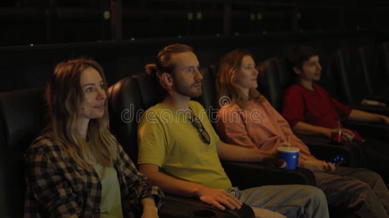 Groep diverse jonge vrienden in een bioscoop kwam kijken naar een film op een groot scherm