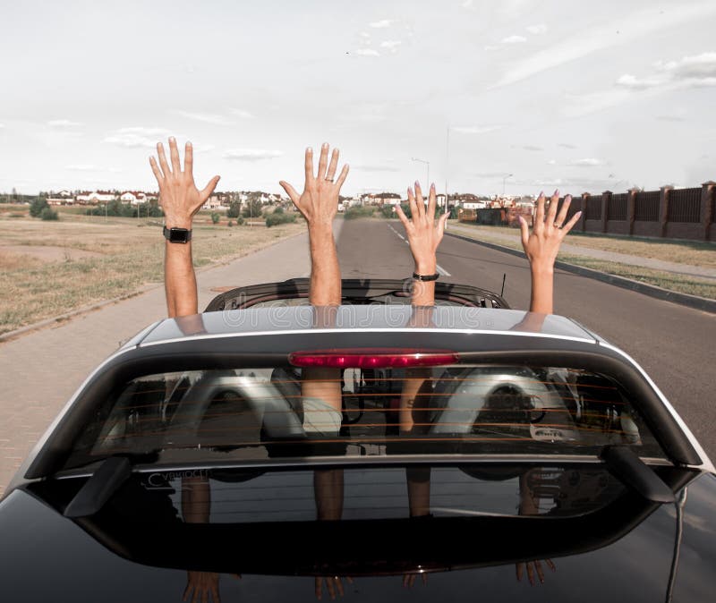 Groep gelukkige jongeren die van een convertibele auto golven royalty-vrije stock fotografie Groep gelukkige jongeren die van een convertibele auto golven royalty-vrije stock fotografie