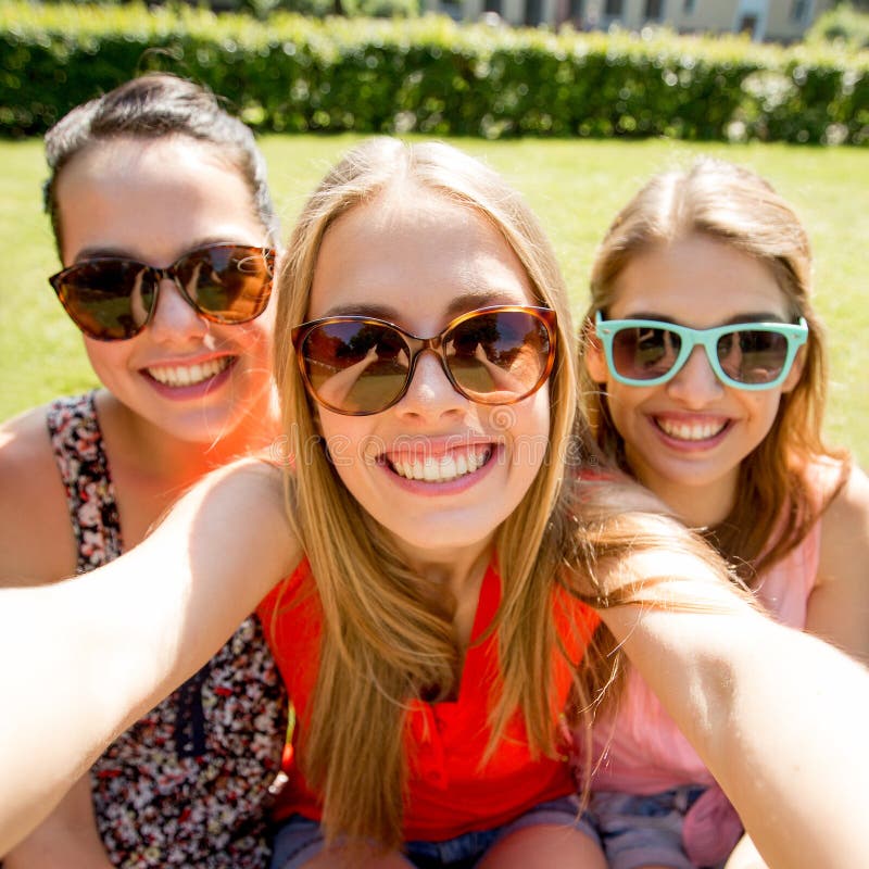 Groep glimlachende tienermeisjes die selfie in park nemen royalty-vrije stock fotografie Groep glimlachende tienermeisjes die selfie in park nemen royalty-vrije stock fotografie