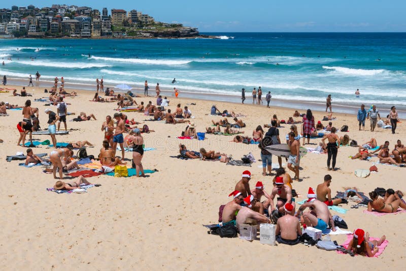 Groep jonge mensen die Kerstmanhoeden op Kerstmisvooravond dragen op Bondi-strand Sydney Australia stock afbeelding Groep jonge mensen die Kerstmanhoeden op Kerstmisvooravond dragen op Bondi-strand Sydney Australia stock afbeelding