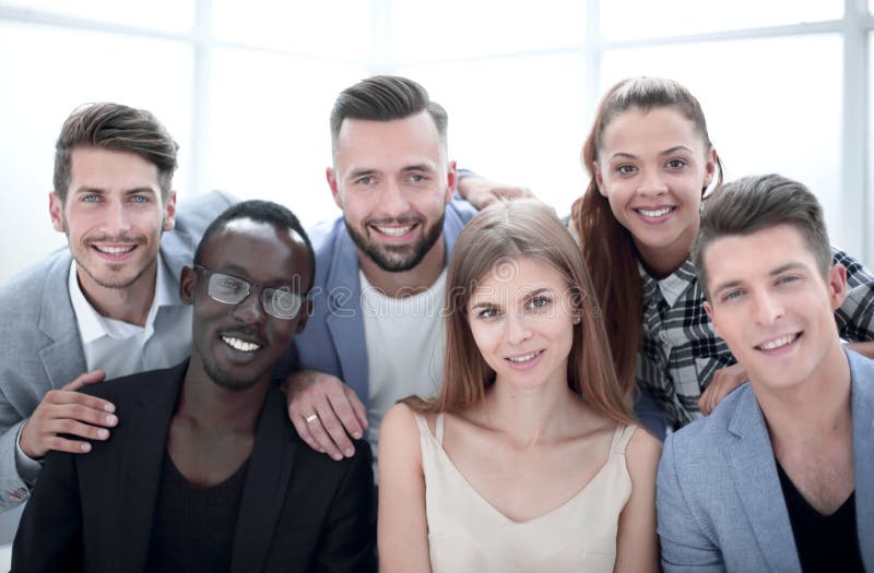 Groep jonge stafmedewerkers die bij camera tijdens een het werkvergadering glimlachen stock fotografie Groep jonge stafmedewerkers die bij camera tijdens een het werkvergadering glimlachen stock fotografie