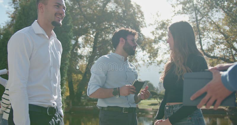 Groep jonge universitaire studenten die in een sunny park aan een gesprek deelnemen.