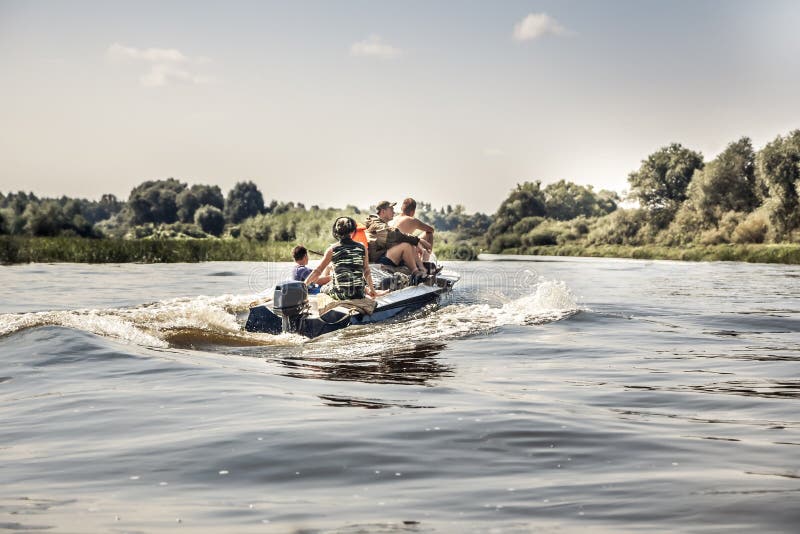 Groep mensen die op motorboot door rivier in de zomerdag aan de het kamperen plaats tijdens jachtseizoen varen stock fotografie Groep mensen die op motorboot door rivier in de zomerdag aan de het kamperen plaats tijdens jachtseizoen varen stock fotografie