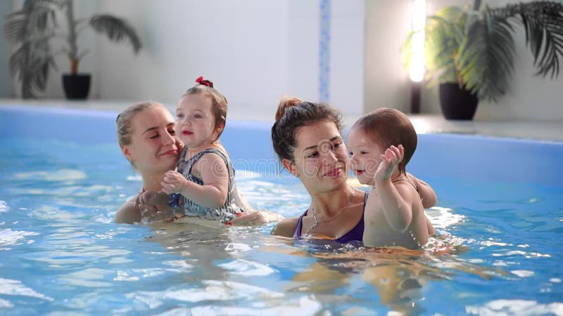 Groep mums met hun babykinderen bij zuigelings zwemmende klasse