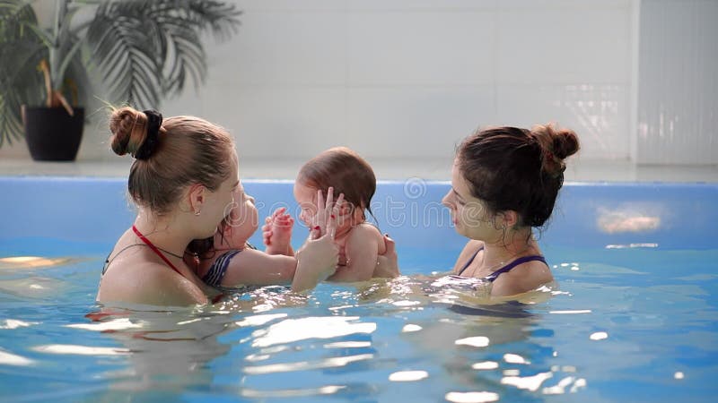 Groep mums met hun babykinderen bij zuigelings zwemmende klasse