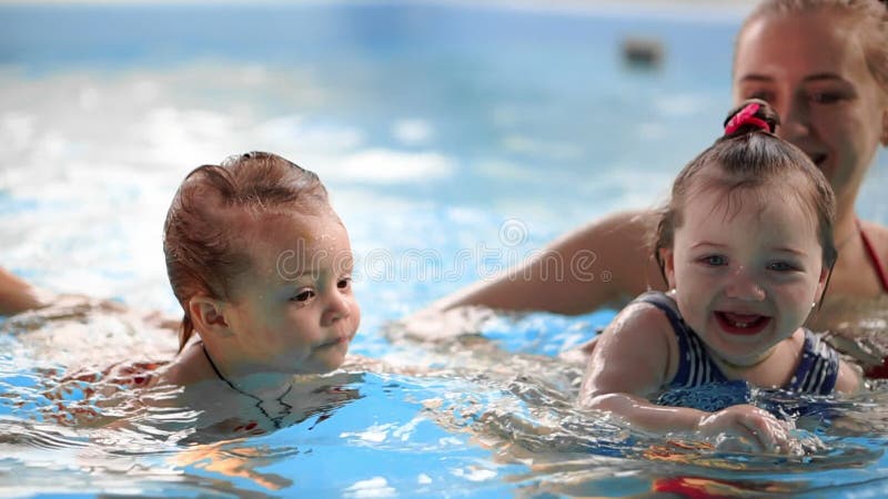 Groep mums met hun babykinderen bij zuigelings zwemmende klasse