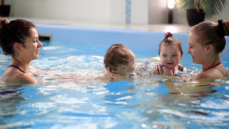 Groep mums met hun babykinderen bij zuigelings zwemmende klasse